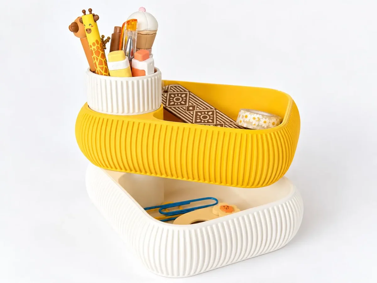 The Nōdo rotating organizer in yellow and cream, holding stationery.